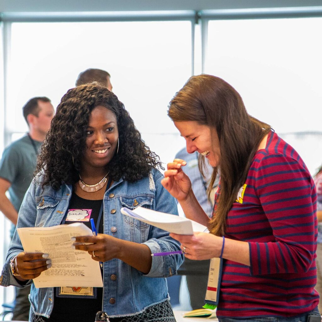 two educators reading from a document. One laughs