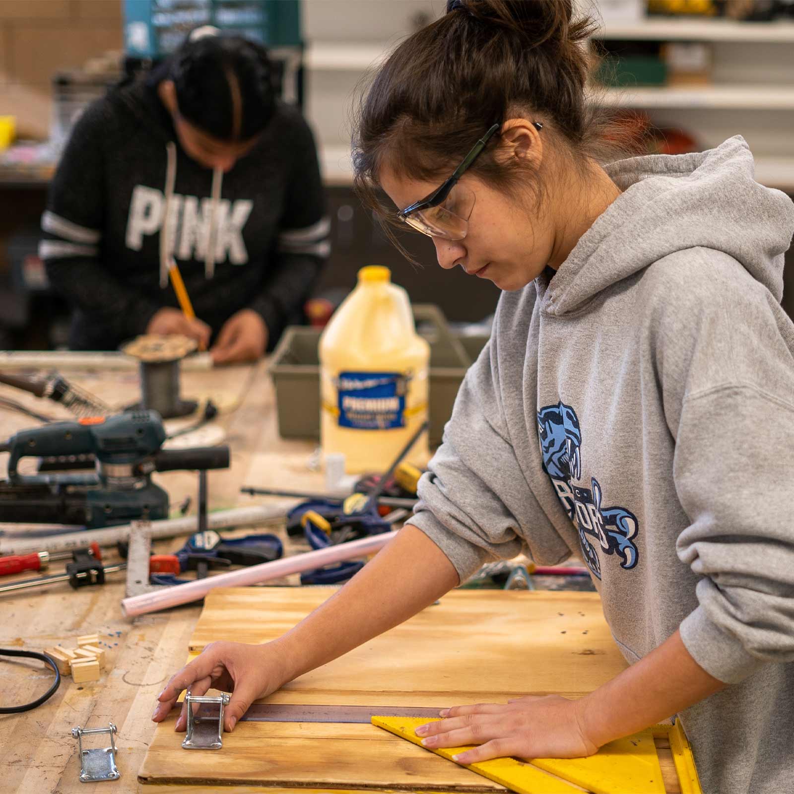 Students wearing safety glasses working in a woodshop